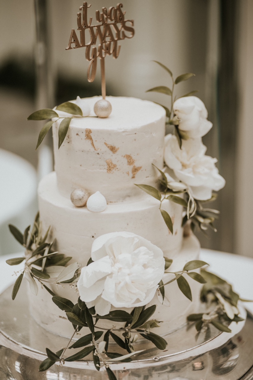Beautiful buttercream wedding cake decorated with gold accents, white peonies and greenery. Buxted Park Hotel, Sussex. Photo by Nataly J Photography