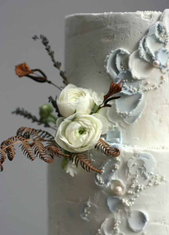 Textured buttercream wedding cake with fresh ranunculus and dried bracken