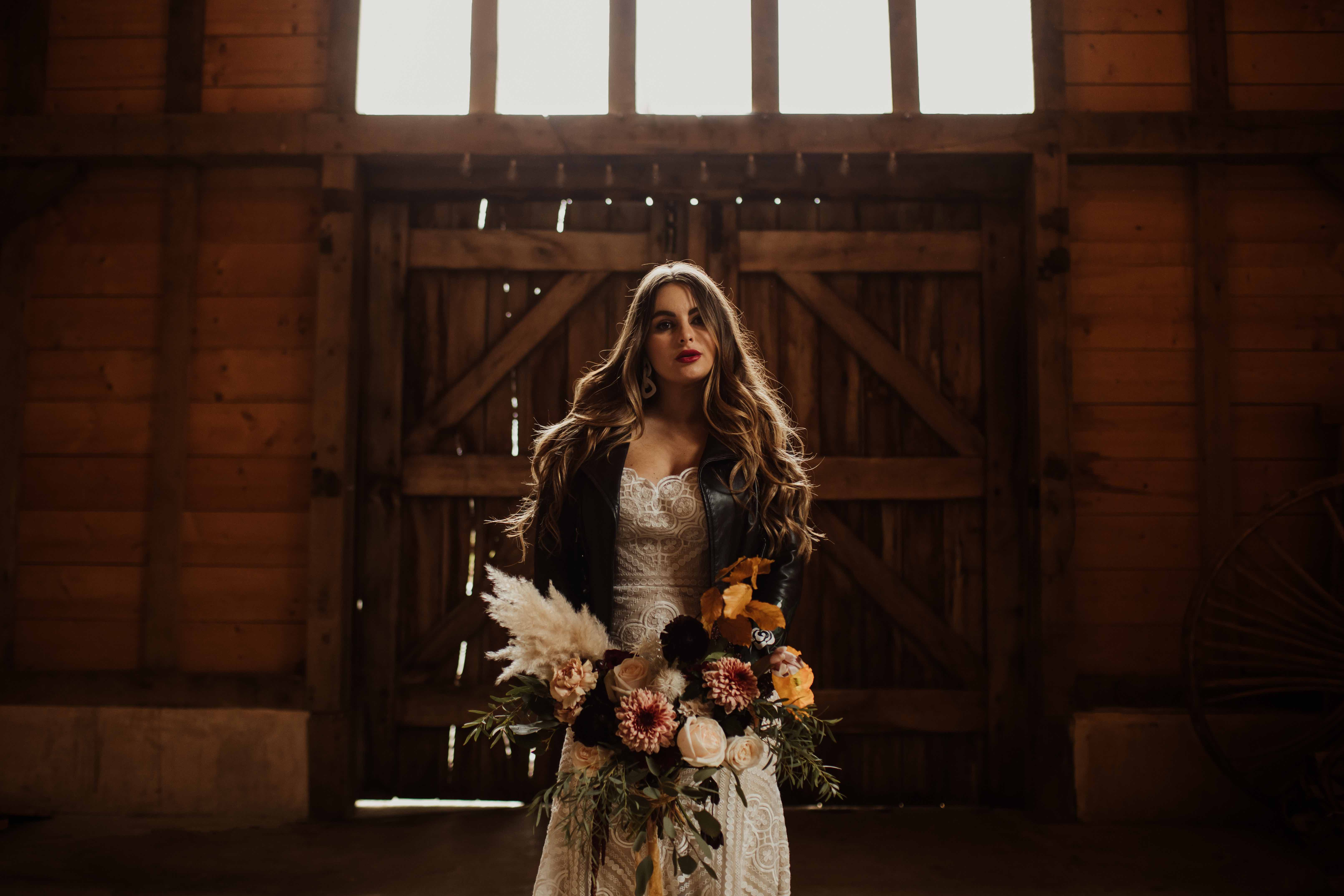 Cool boho bride with long hair and leather jacket | Rustic barn backdrop