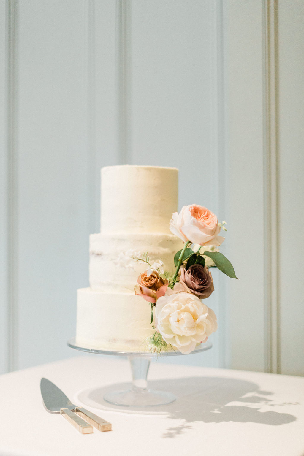 Understated, simply beautiful buttercream wedding cake decorated with a flourish of fresh flowers. Photo by Jacob & Pauline