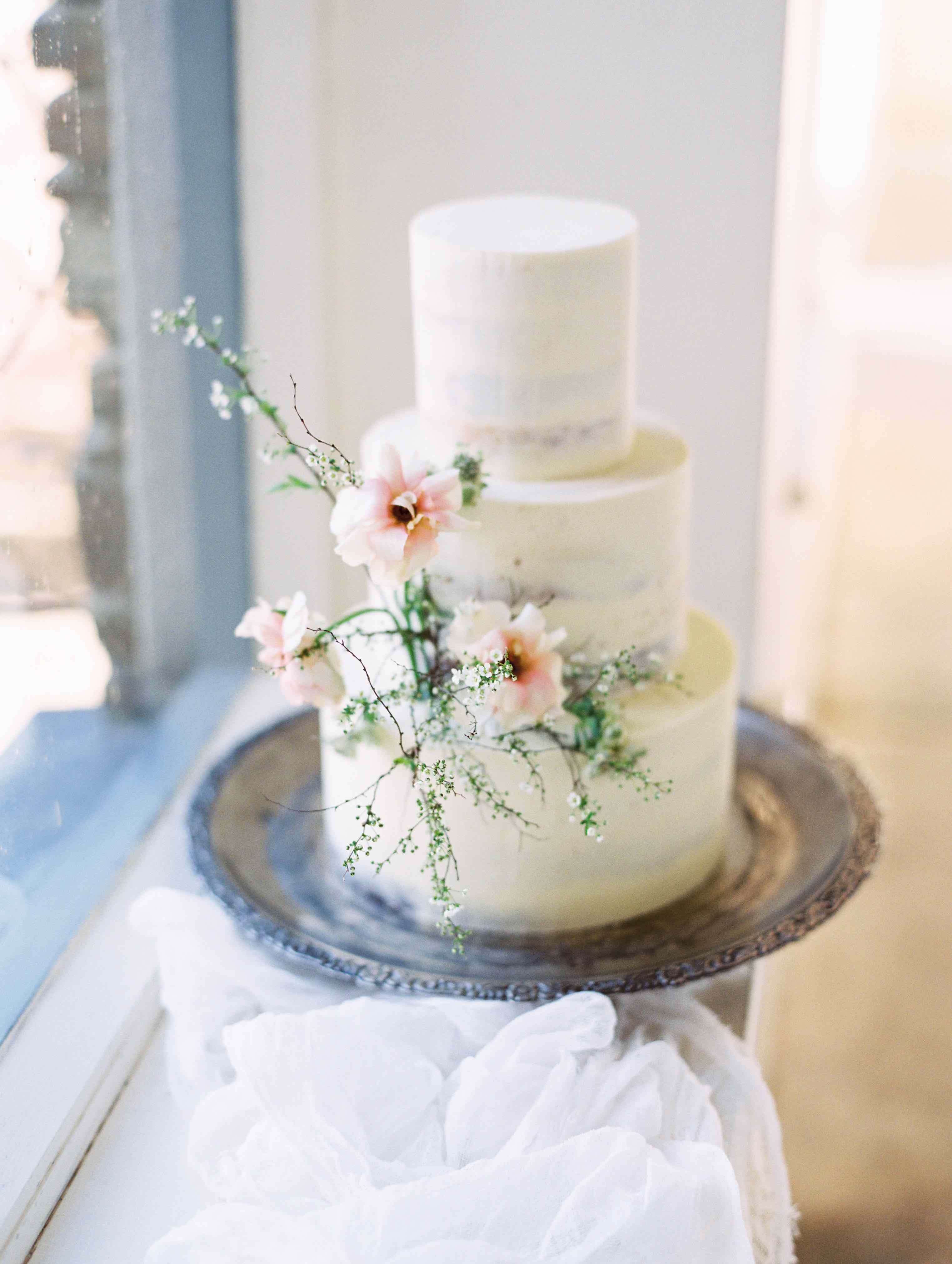 Gentle, delicate Spring flowers on a semi-naked buttercream wedding cake