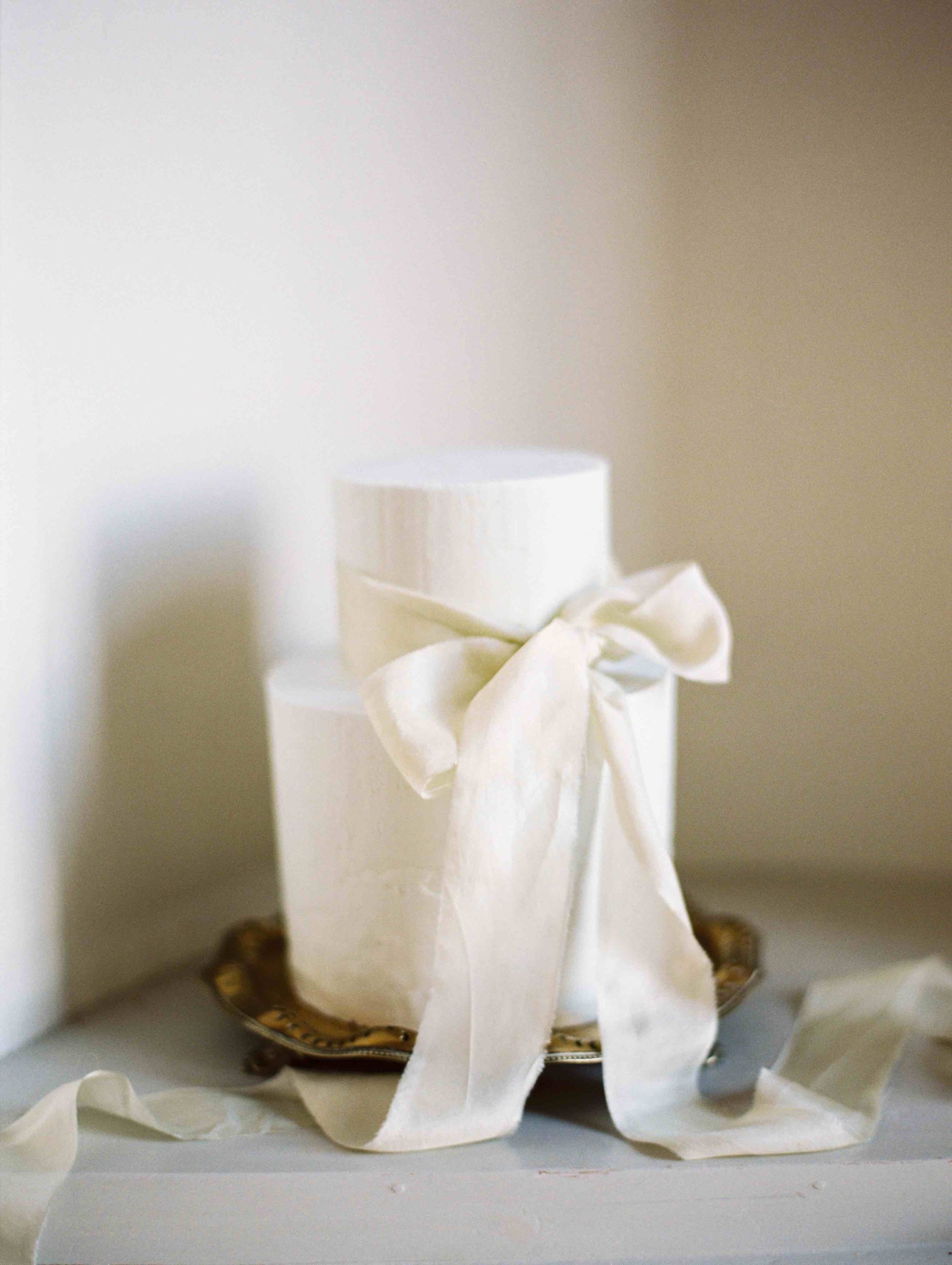 Understated elegant buttercream wedding cake tied with a silk ribbon. Featured on Style Me Pretty