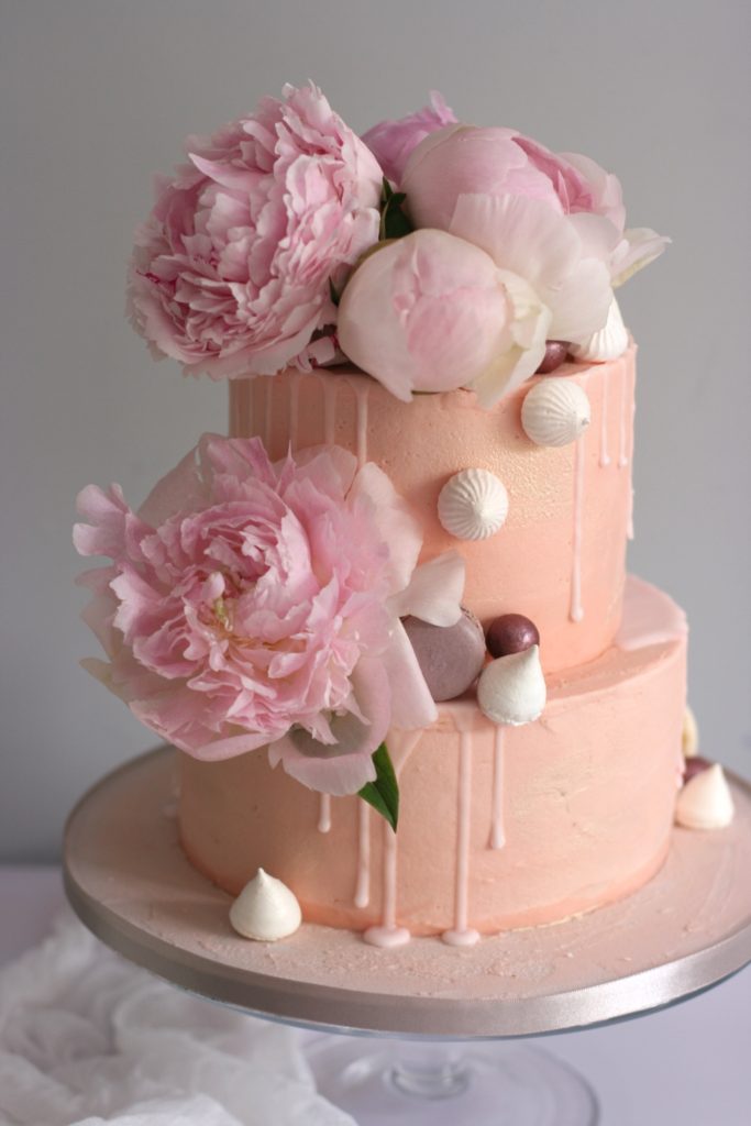 Blush pink buttercream decorated with fresh pink peonies, macaron and meringue kisses