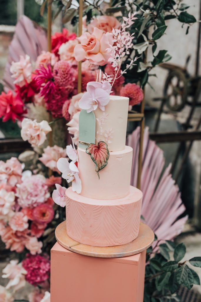 Pink tiered buttercream wedding cake decorated with fresh orchids and modern sugar details