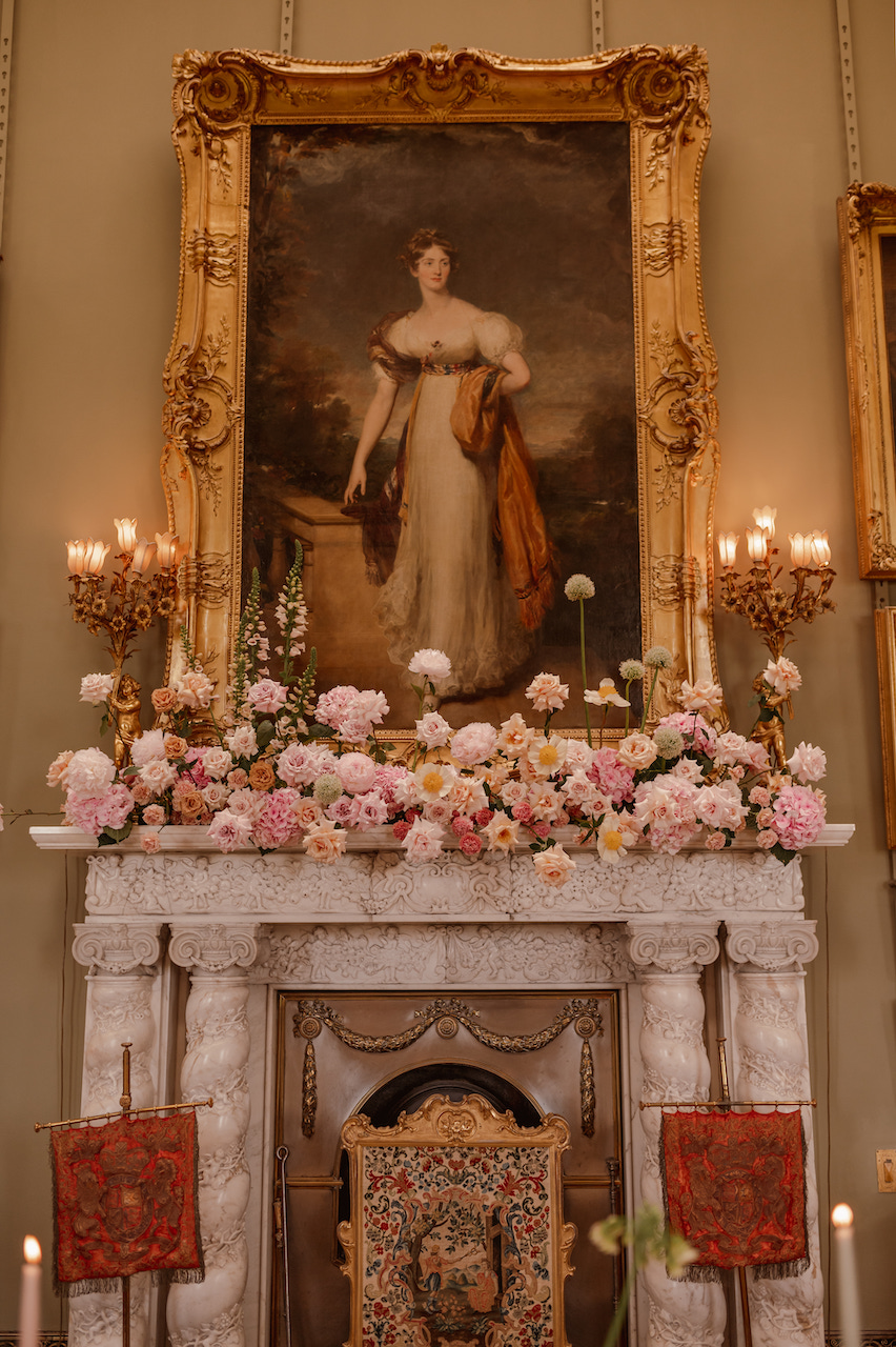 Modern stylish floral installation with peach, blush and pink flowers in Picture Gallery at Somerley House Hampshire UK