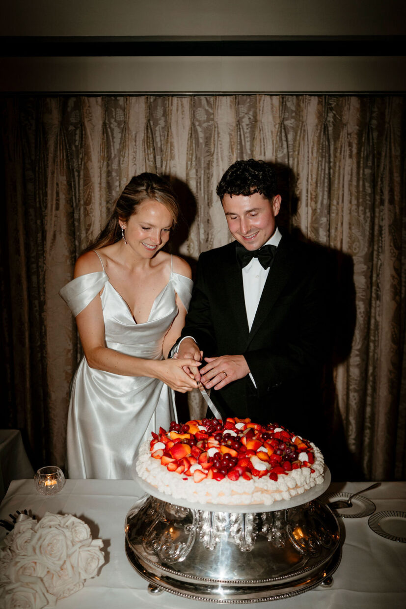 Couple cutting millefoglie Italian wedding cake decorated with Summer berries and grapes at The Goring Hotel London | The Unbridled Photography