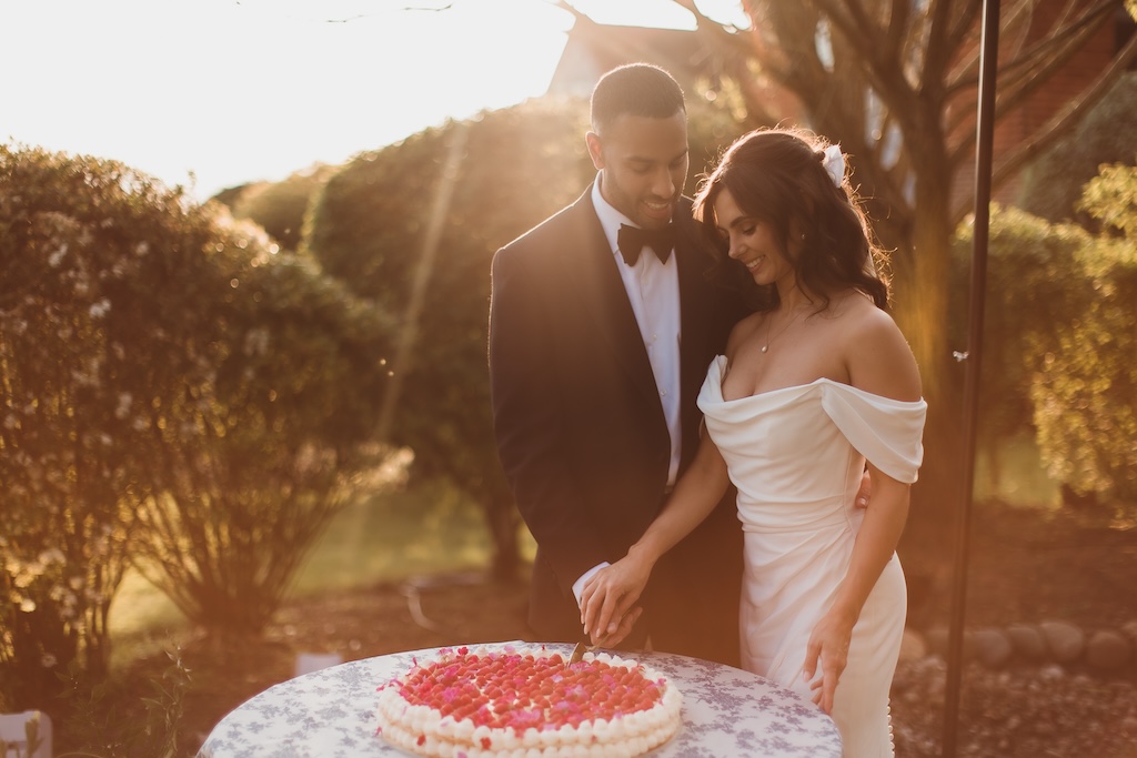 Bride and groom cutting italian wedding cake in outdoor setting